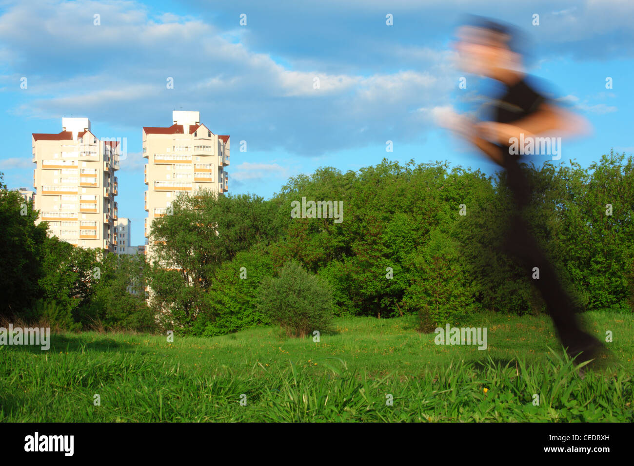 Motion Blur uomo correre nel parco e due edifici Foto Stock