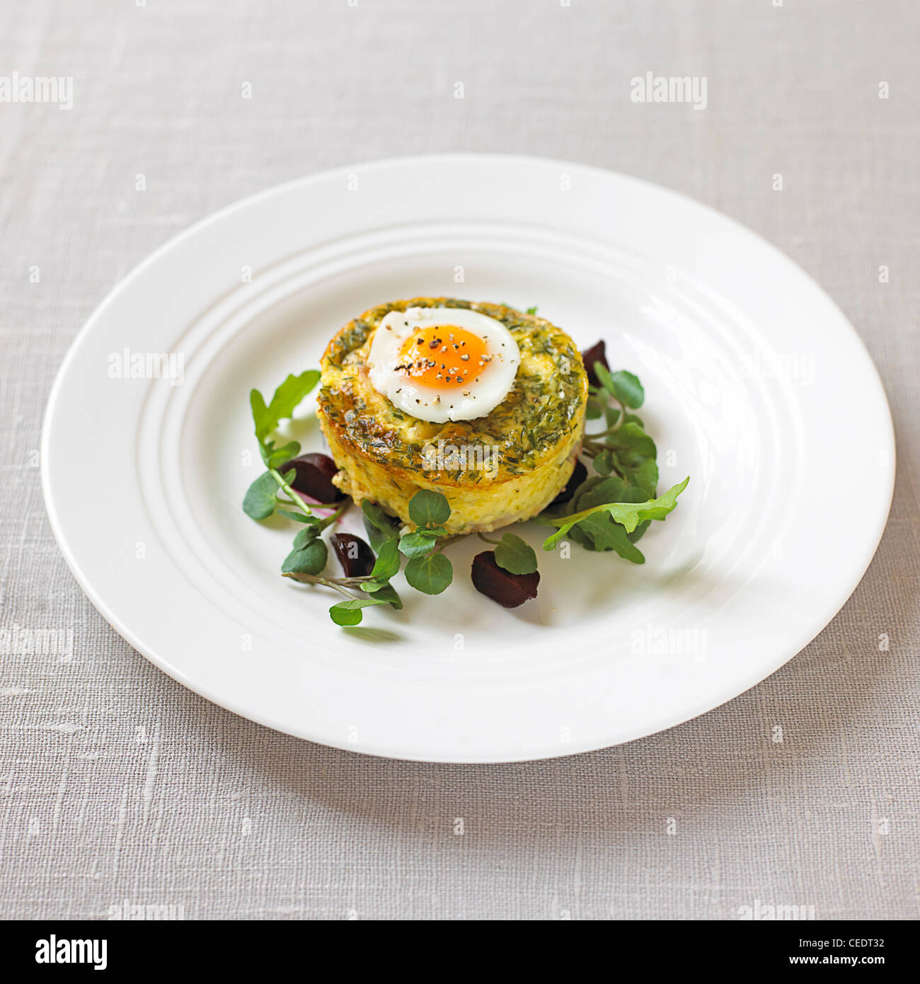 Eglefino affumicato timballo con bollito di quaglia uovo su una piastra bianca e guarnita con crescione Foto Stock