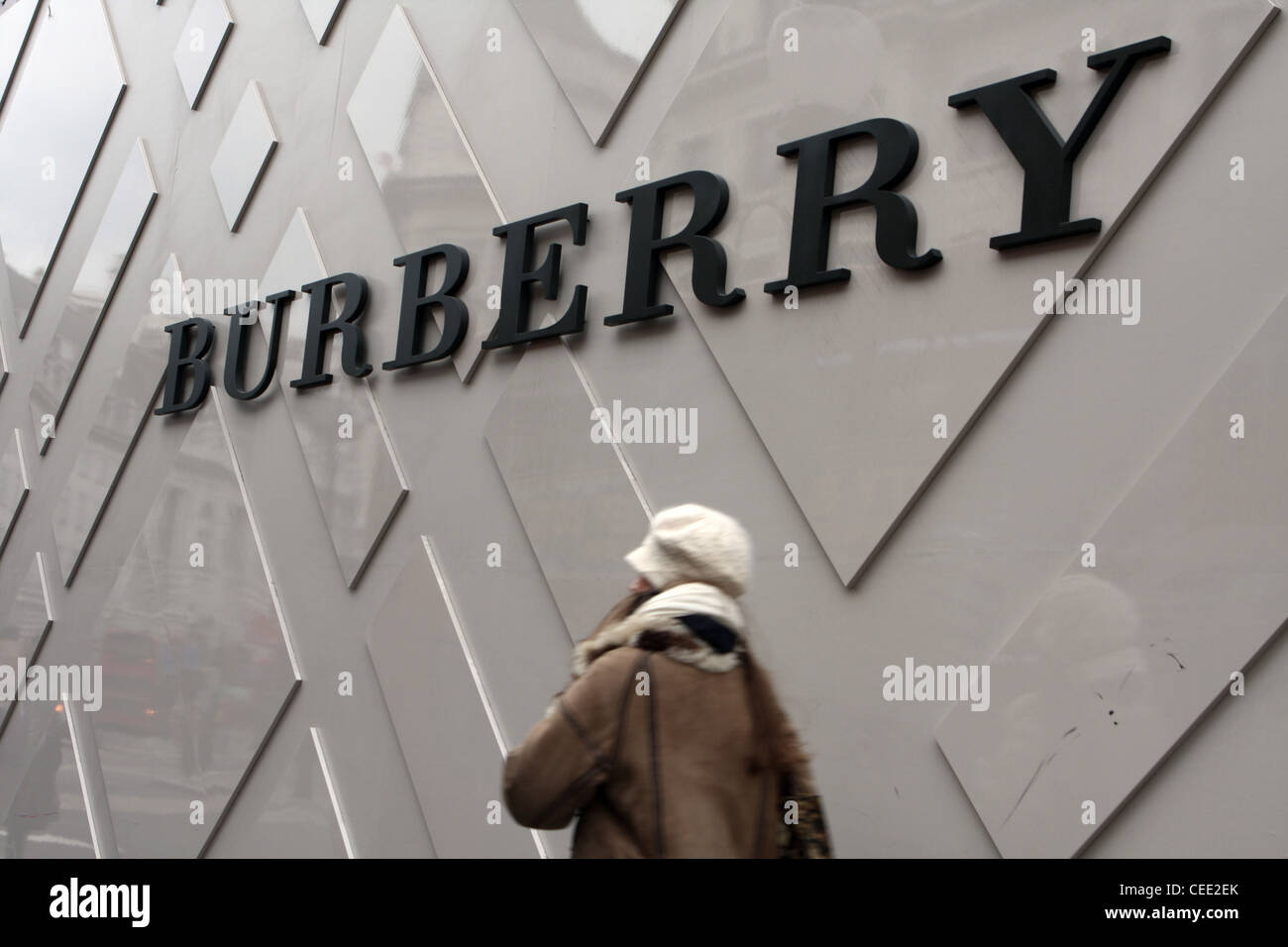 Una femmina a piedi passato un segno Burberry al di fuori del Regent Street negozio Foto Stock