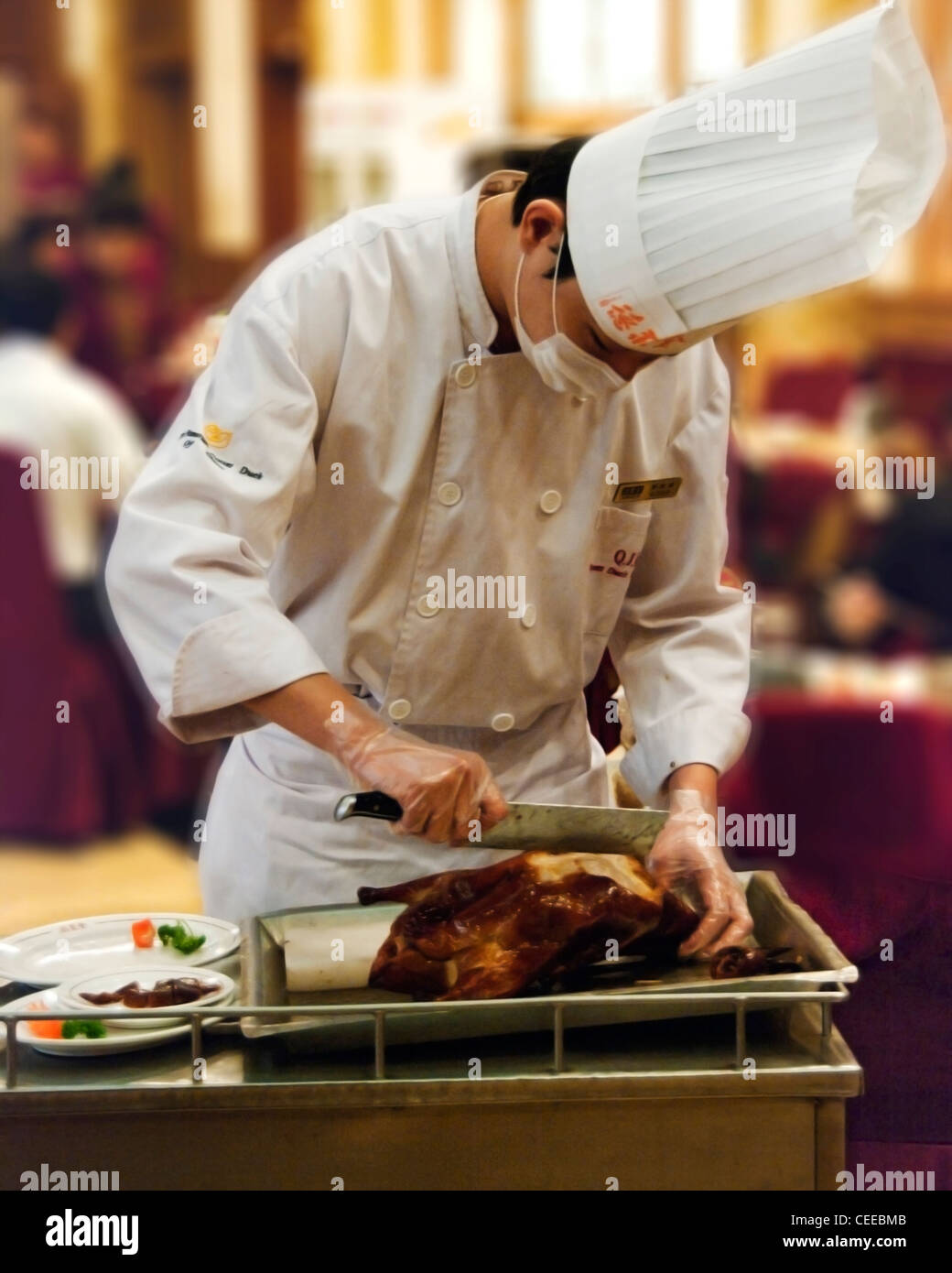 Server sta ritagliandosi fette di carne da un arrosto di anatra alla pechinese in questo ristorante di Pechino Foto Stock
