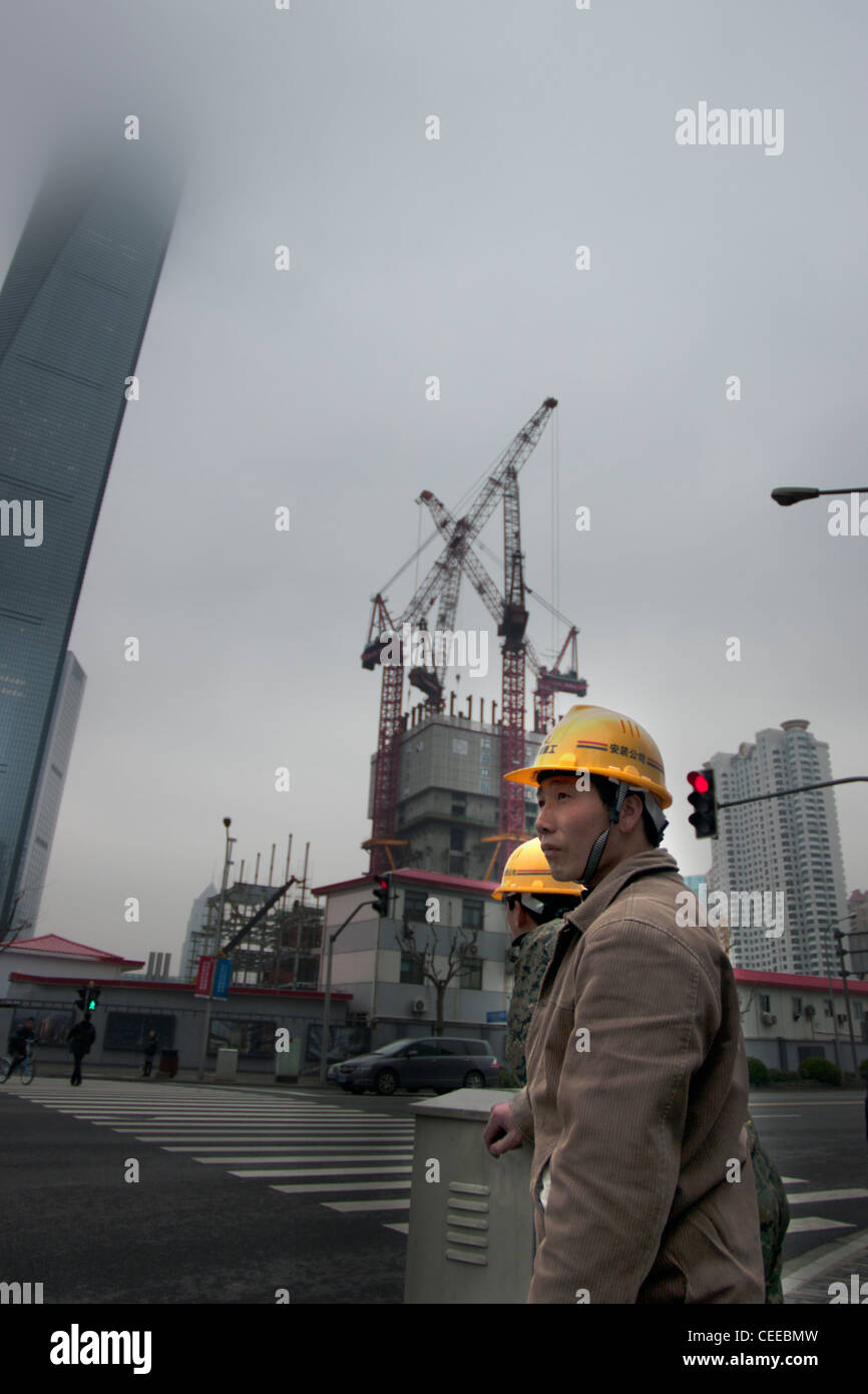 Elmetto che indossa il cinese operai edili diretta a un sito di lavoro a Shanghai Foto Stock