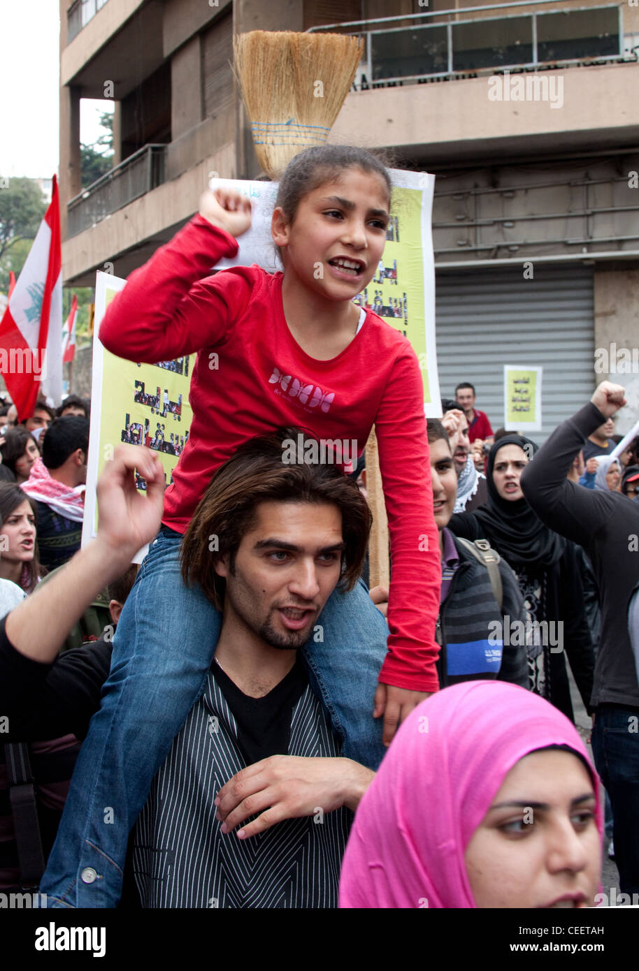 Ragazza giovane chants slogan politici come lei è portato sulle spalle del giovane alla manifestazione politica a Beirut, Libano Foto Stock