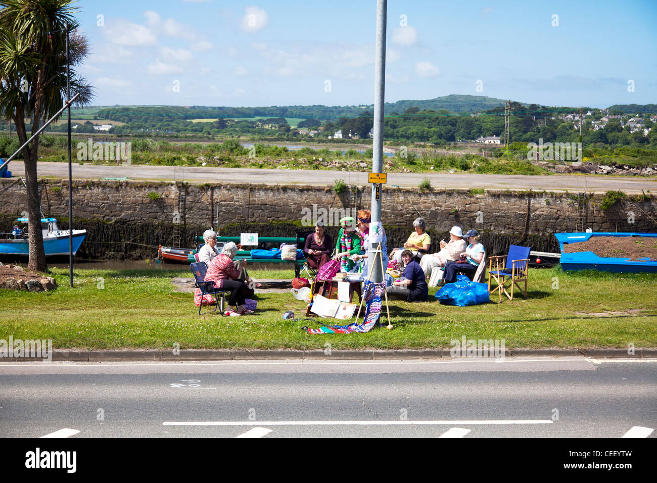 Un branco di nonni sul lato strada in Hayle, Cornwall, Inghilterra hosting di un club maglieria mostra mercanzia come macchine passano Foto Stock