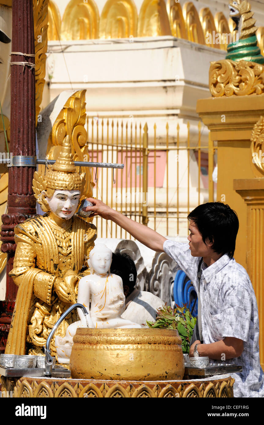 Devoto pellegrino pour versando acqua facendo offrendo alla statua del Buddha post planetari Shwedagon pagoda myanmar Foto Stock