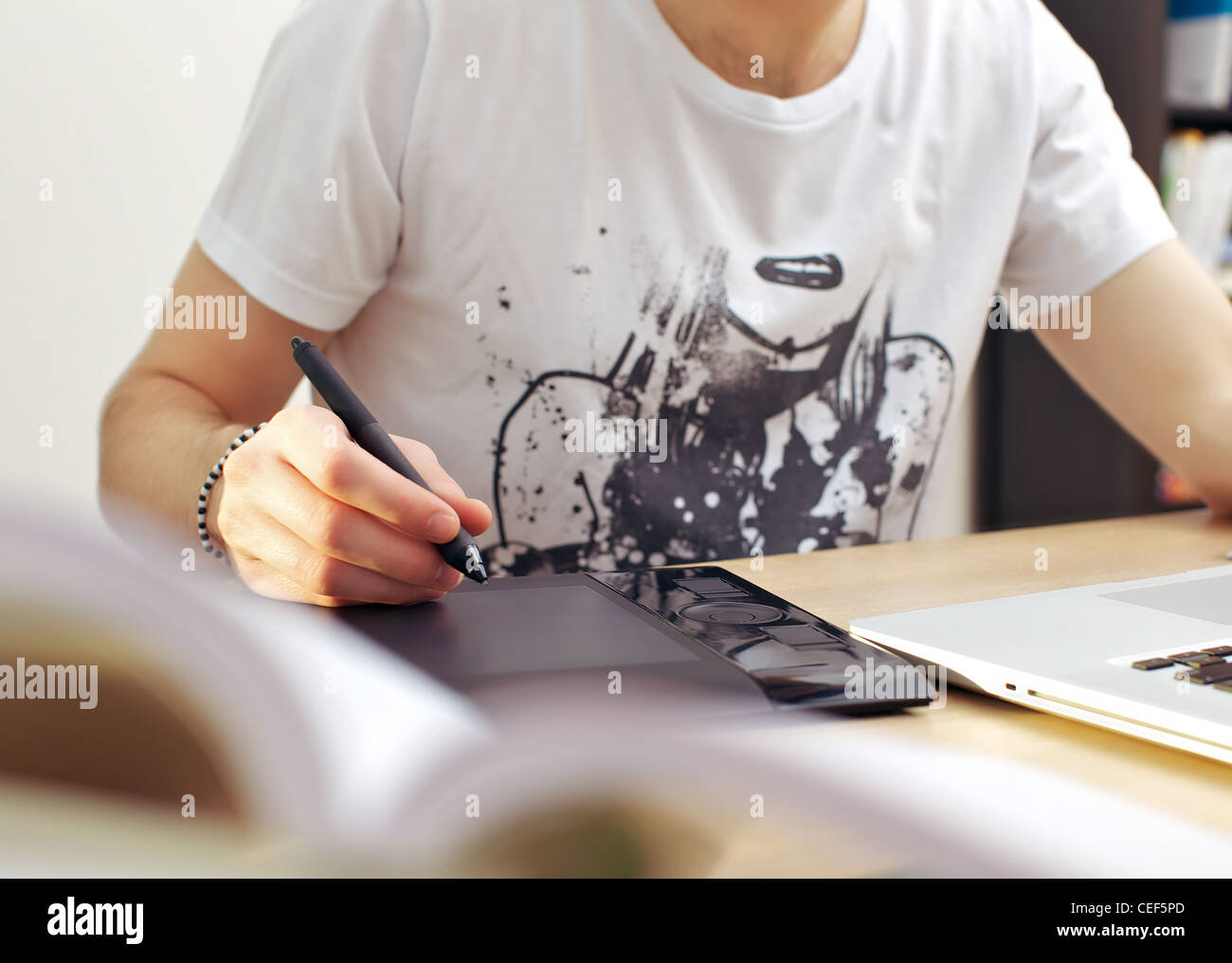 Uomo con tavoletta grafica mentre si è seduti davanti al suo computer portatile a una scrivania. Foto Stock