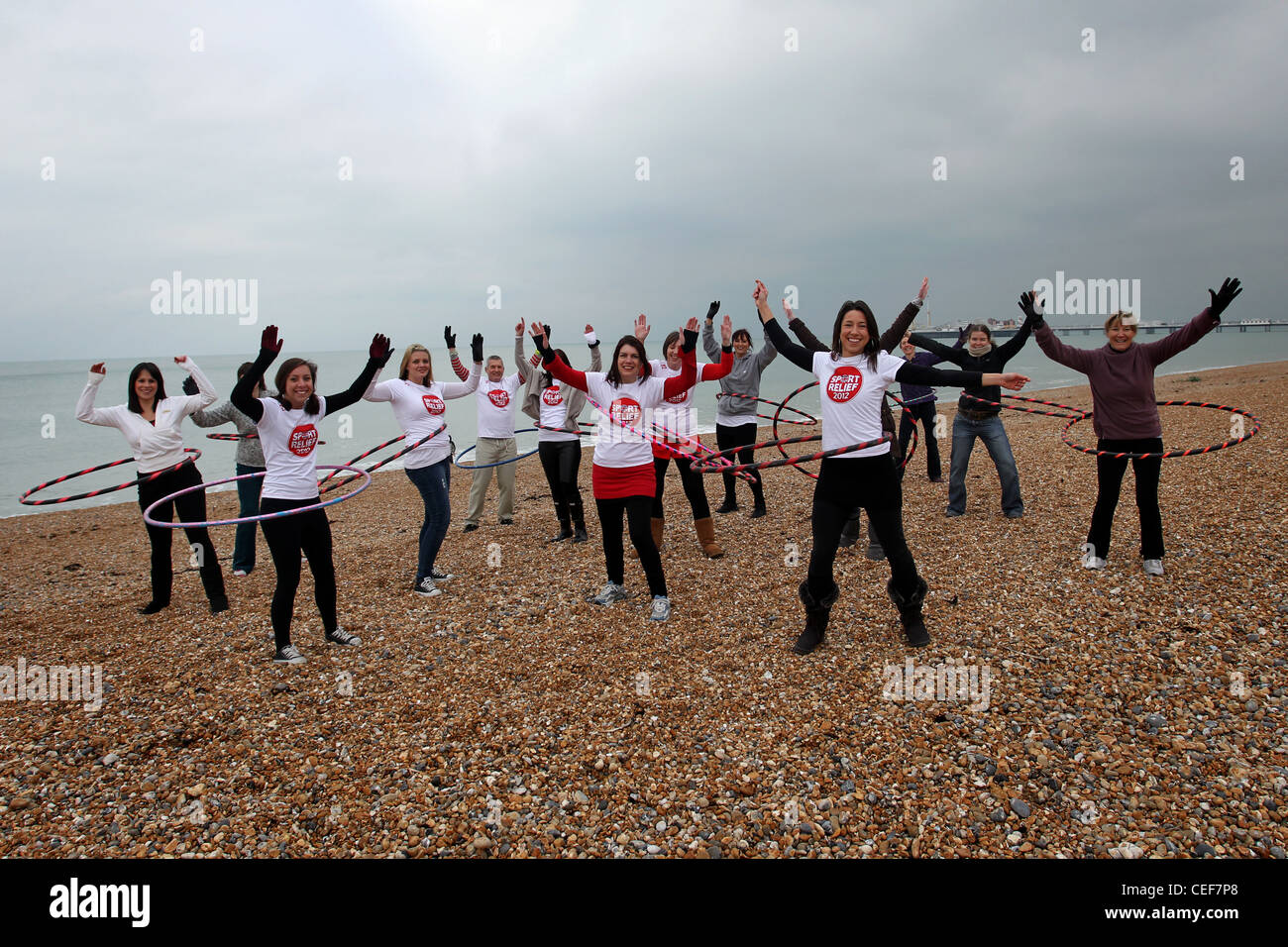 Gruppo di persone che partecipano a sport Relief 2012, Hula cerchiatura in strada. Essi sono illustrati sulla Spiaggia di Brighton, East Sussex. Foto Stock
