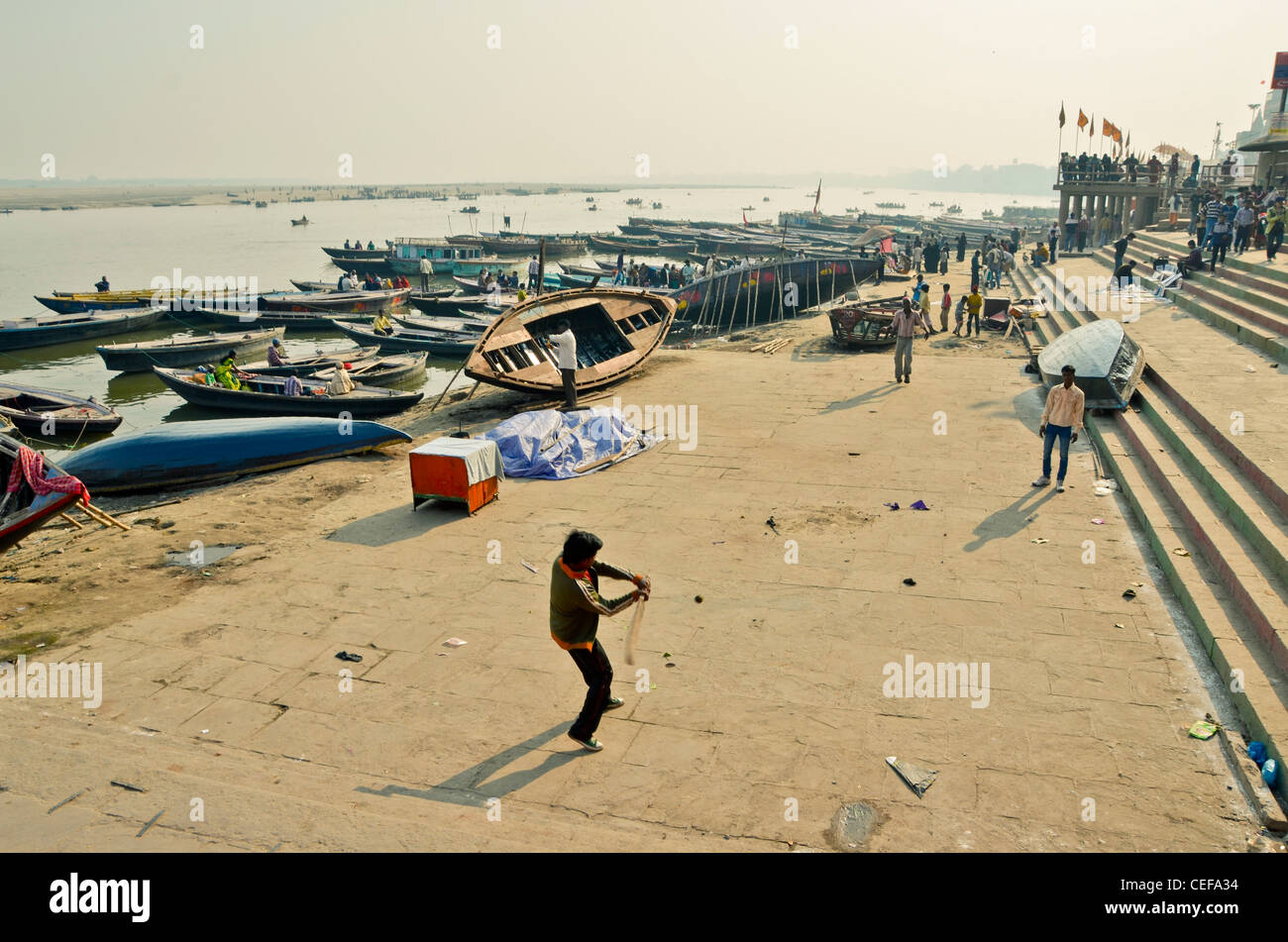La gente del posto a giocare a cricket lungo il fiume santo di Varanasi, India Foto Stock