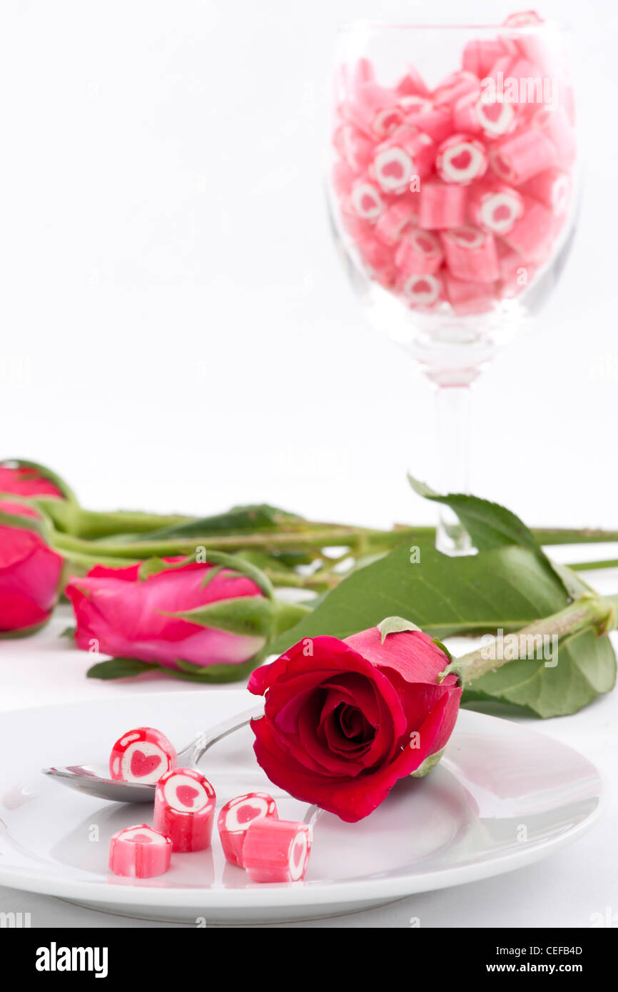 Serie di san valentino, Candy sul piatto con rosa su sfondo bianco Foto Stock