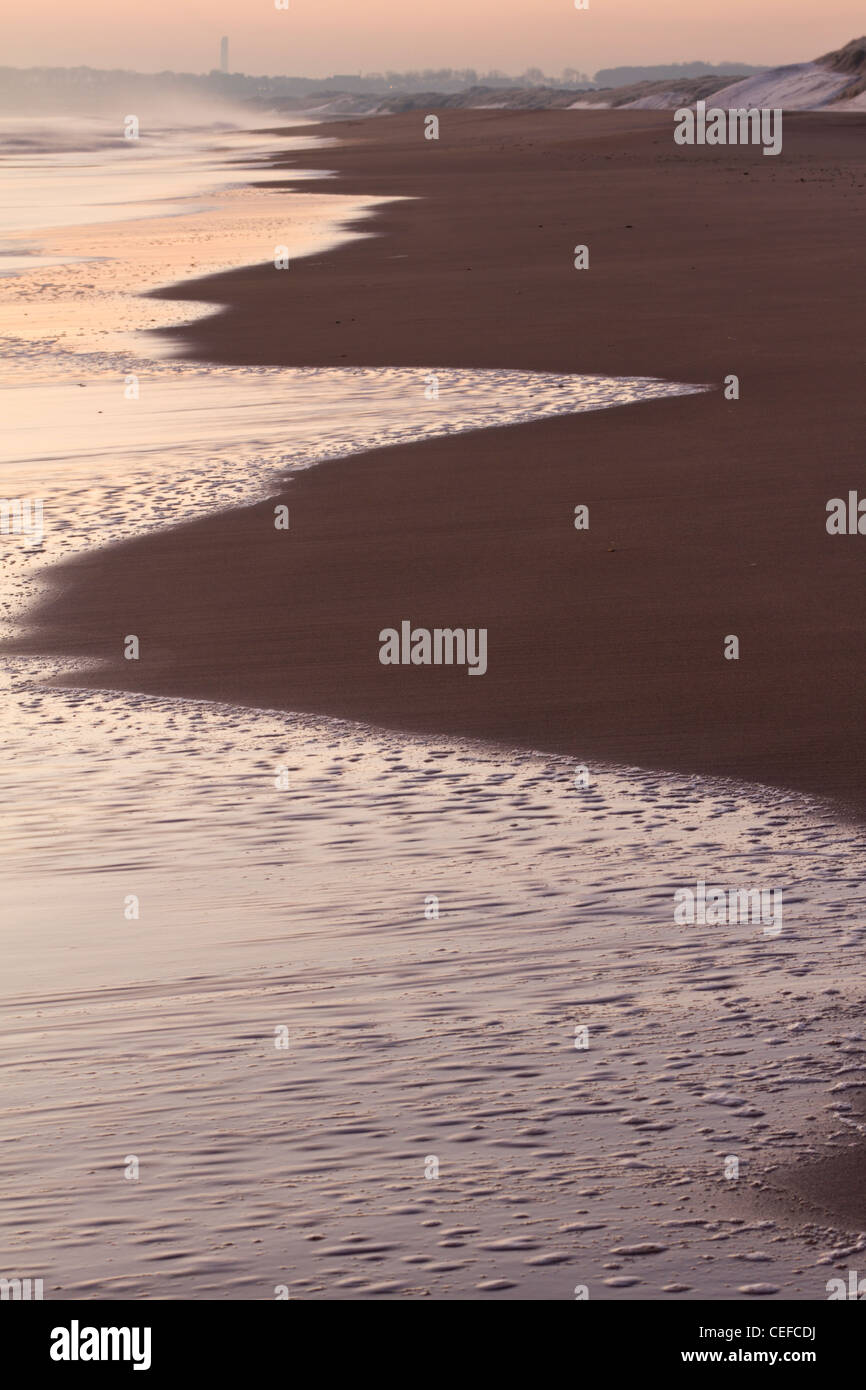 Sabbia bagnata sulla spiaggia di Druridge Bay con Cresswell nella distanza, Northumberland, Inghilterra Foto Stock
