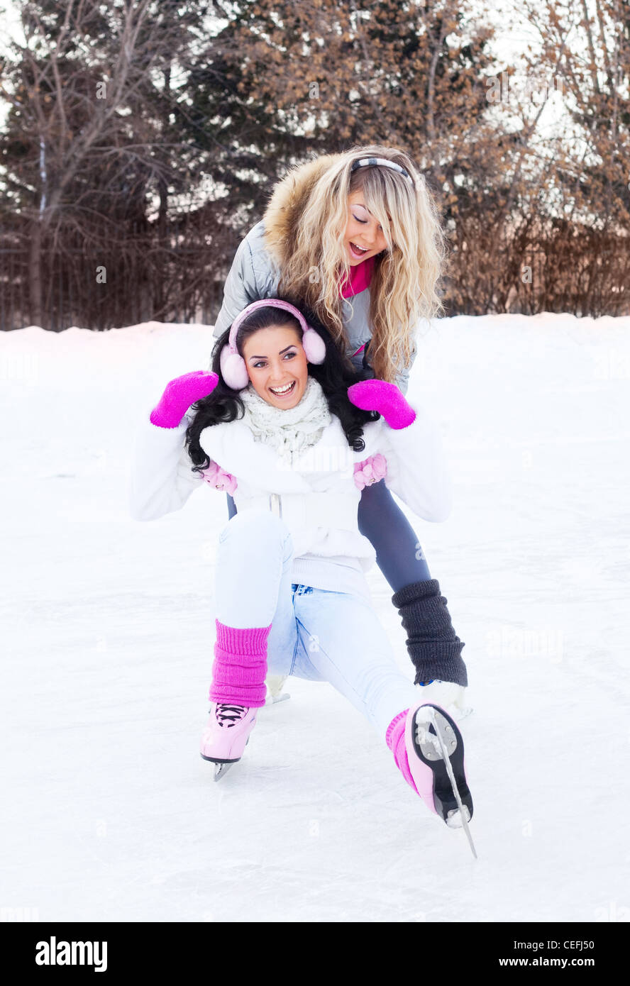 Felice di due giovani donne di pattinaggio sul ghiaccio all'aperto su una giornata invernale Foto Stock