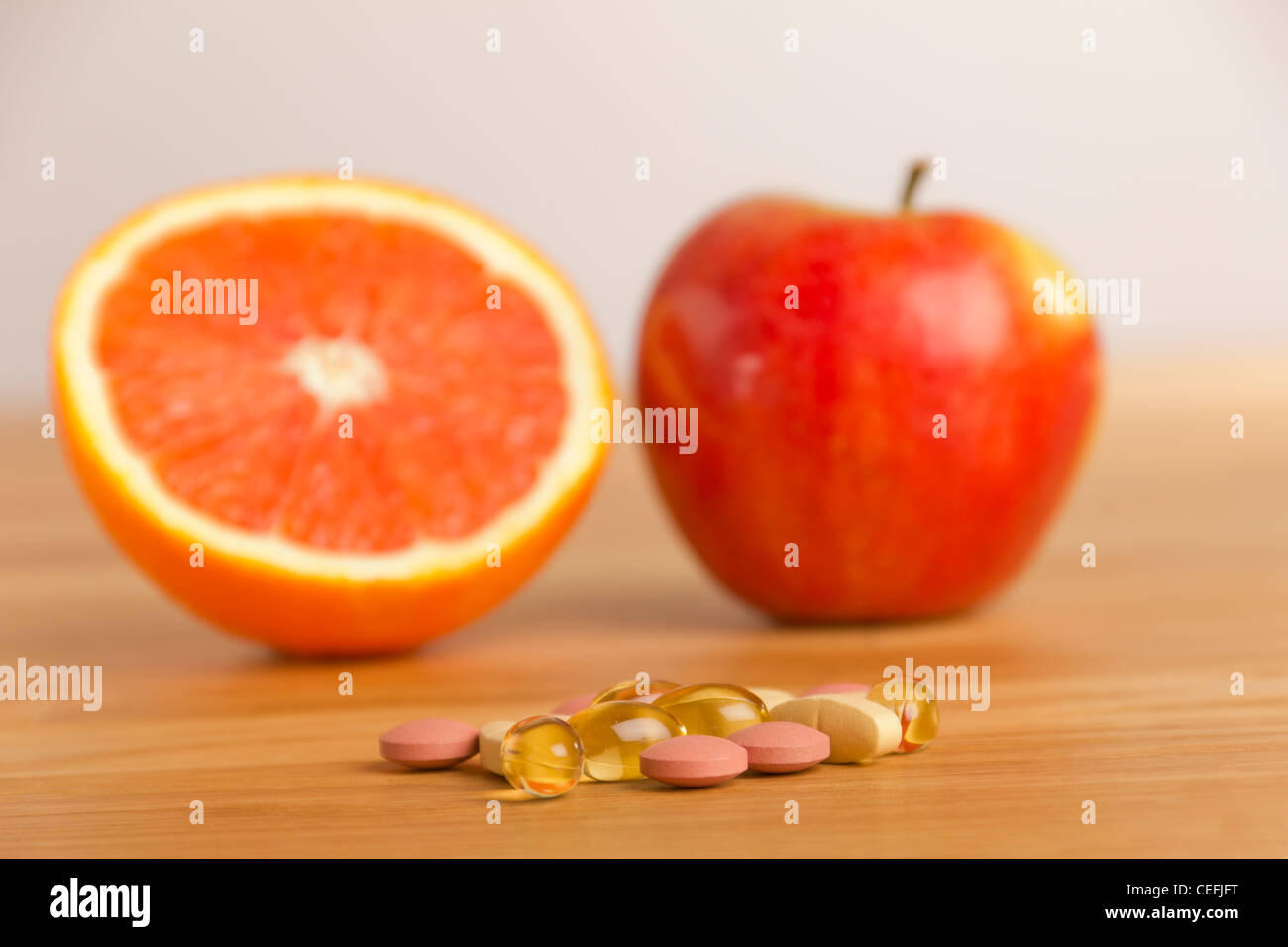 Integratore dietetico giacente su un tavolo, dietro un apple e e arancione Foto Stock