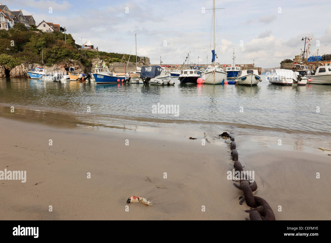 Newquay, Cornwall, Inghilterra, Regno Unito. Catena sulla spiaggia e barche da pesca ormeggiate nel porto Foto Stock