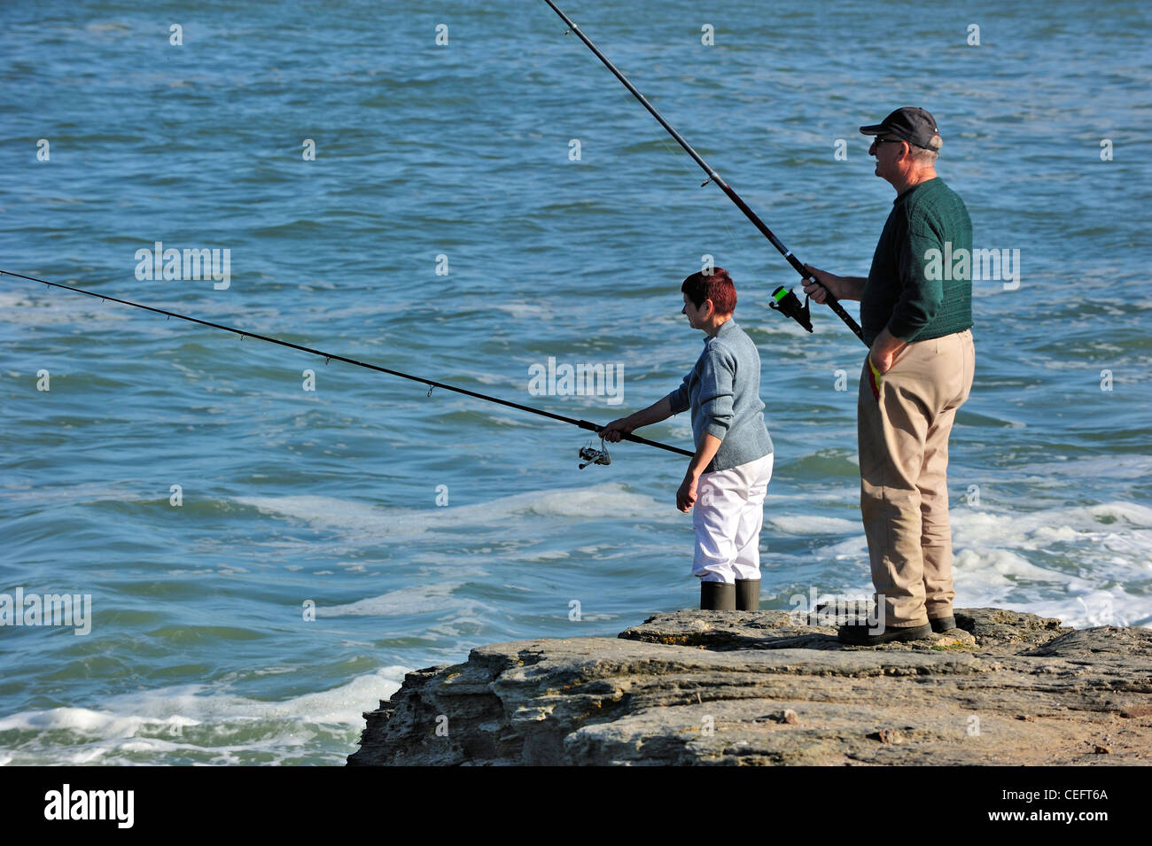 Paio di titolare di pensione o di rendita i pescatori di mare pesca dalla scogliera di Pointe Saint-Gildas / Saint Gildas Point, Loire-Atlantique, Francia Foto Stock