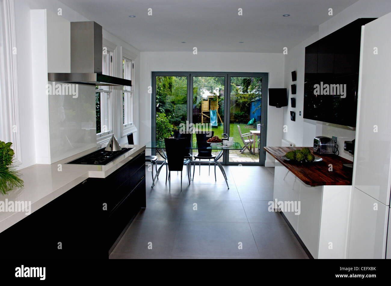 Bianca E Moderna Cucina Sala Da Pranzo Camera Con Pavimento In Nero E Vetro Aperto Sul Patio Giardino Foto Stock Alamy