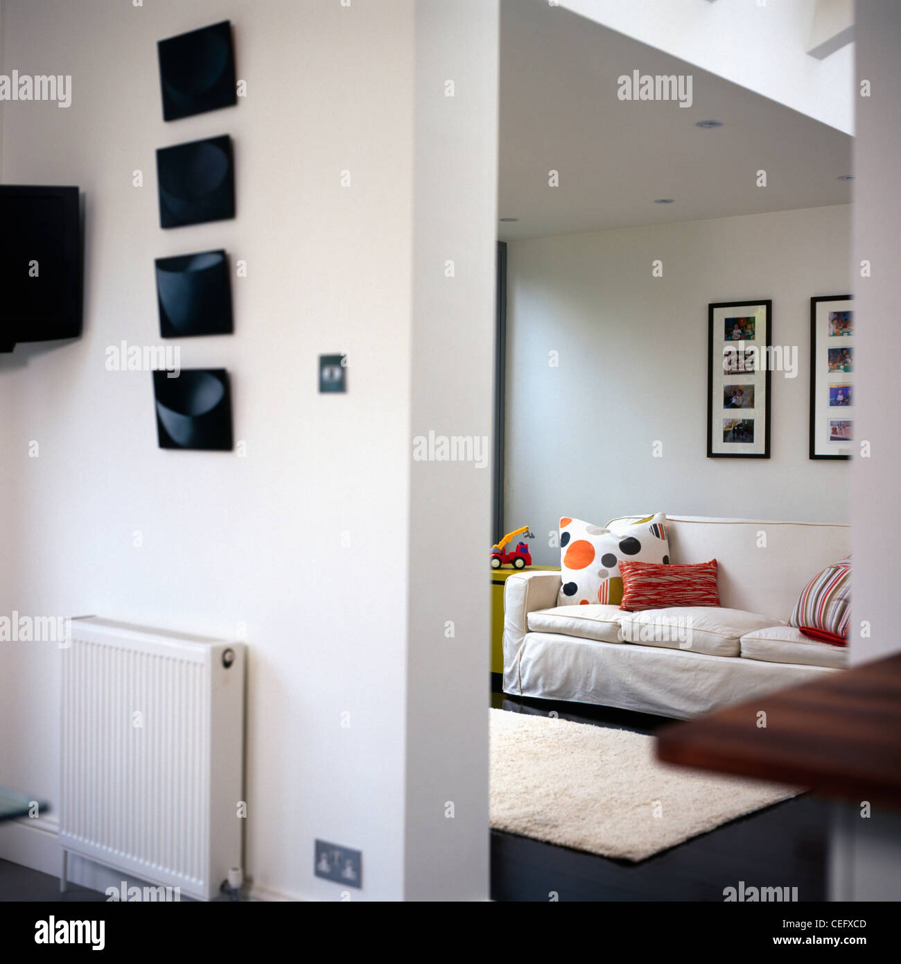 Le immagini sulla parete sopra il radiatore sulla parete divisoria in bianco moderno salotto interno con divano bianco Foto Stock