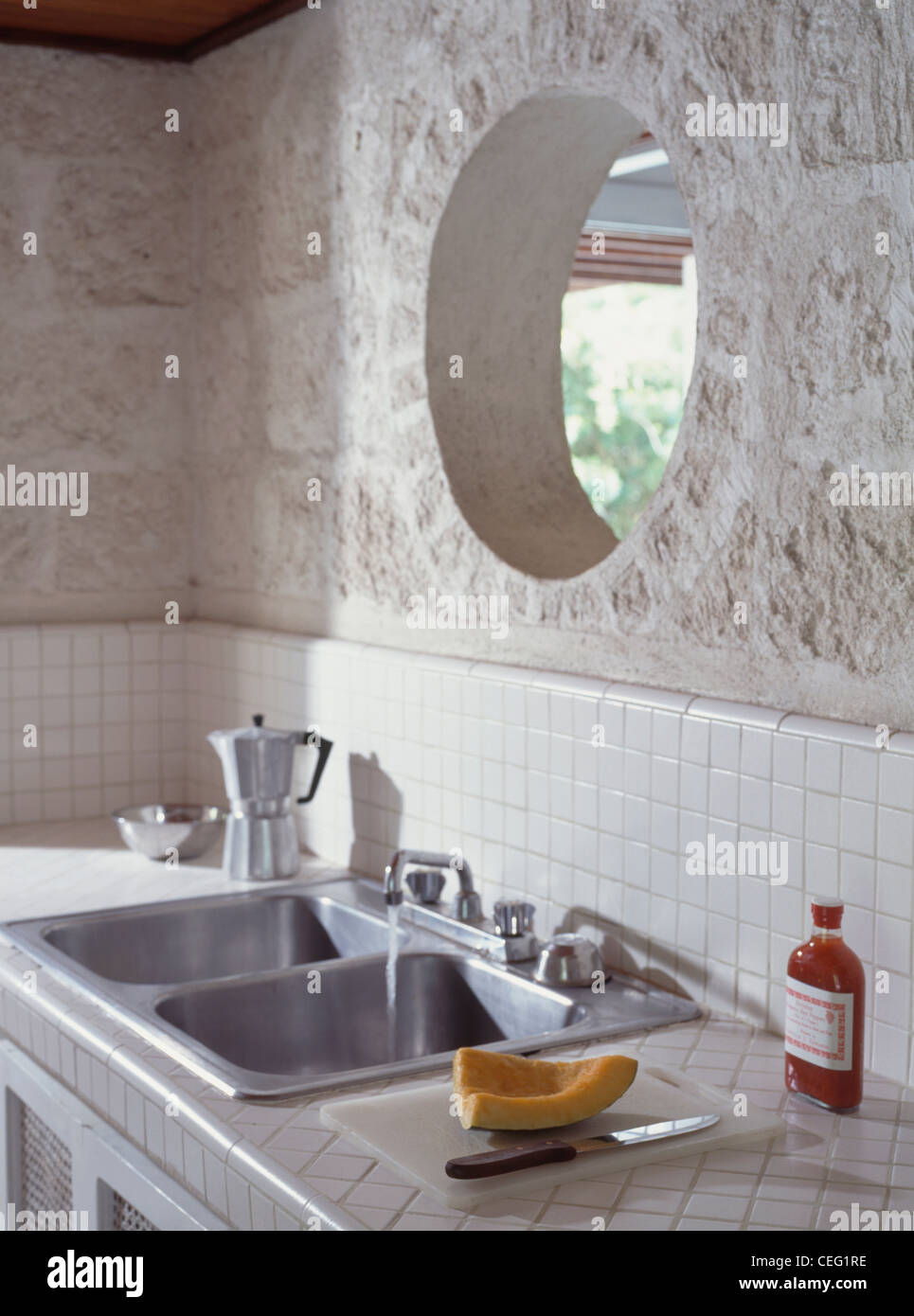 Circolare finestra interna in pietra grezza parete sopra il doppio in  acciaio inox lavello da cucina Foto stock - Alamy