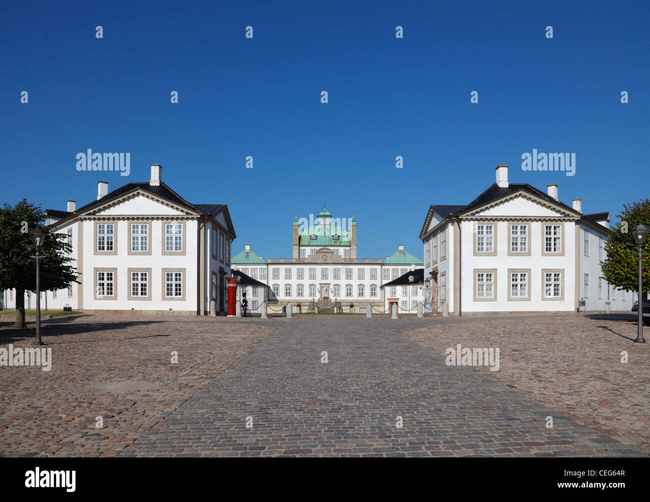 Il Royal Fredensborg Palace di Fredensborg, vicino a Copenhagen, Danimarca. Orso sentinelle della pelle dalla vita reale le protezioni in distanza Foto Stock