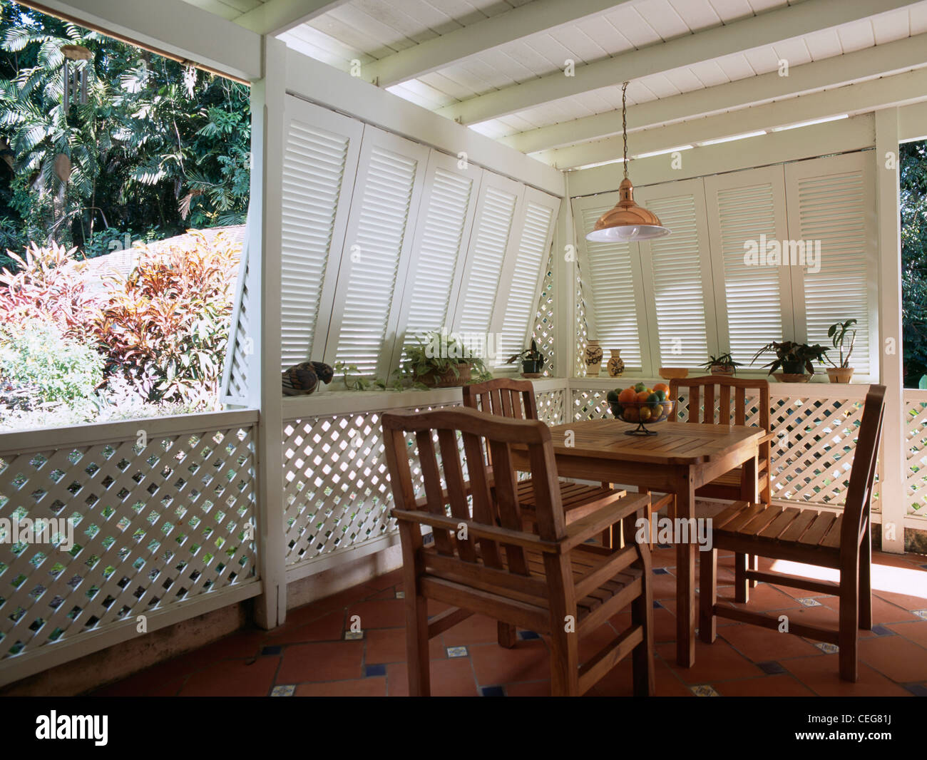 Semplice legno tavolo da pranzo e sedie in un angolo dei Caraibi veranda  bianco con persiane avvolgibili e pavimento piastrellato Foto stock - Alamy