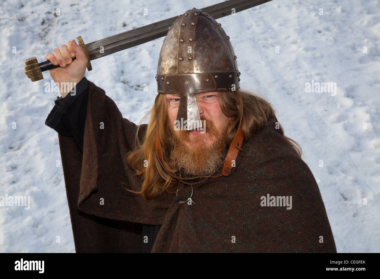 Ingolfui (MR) reenattore medievale islandese vichingo, con barba che indossa casco metallico e porta una spada sollevata; 27° Festival annuale JORVIK a York, Regno Unito Foto Stock