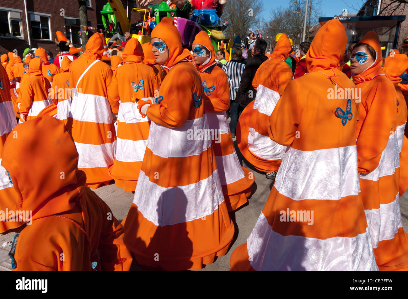 Coloro che si uniscono alla sfilata di carnevale vestito come orange street tralicci Foto Stock