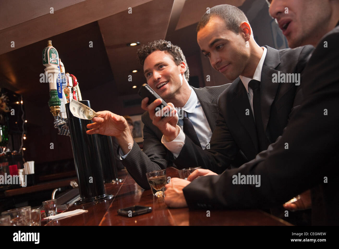 Tre uomini di affari ottenere bevande al bar Foto Stock