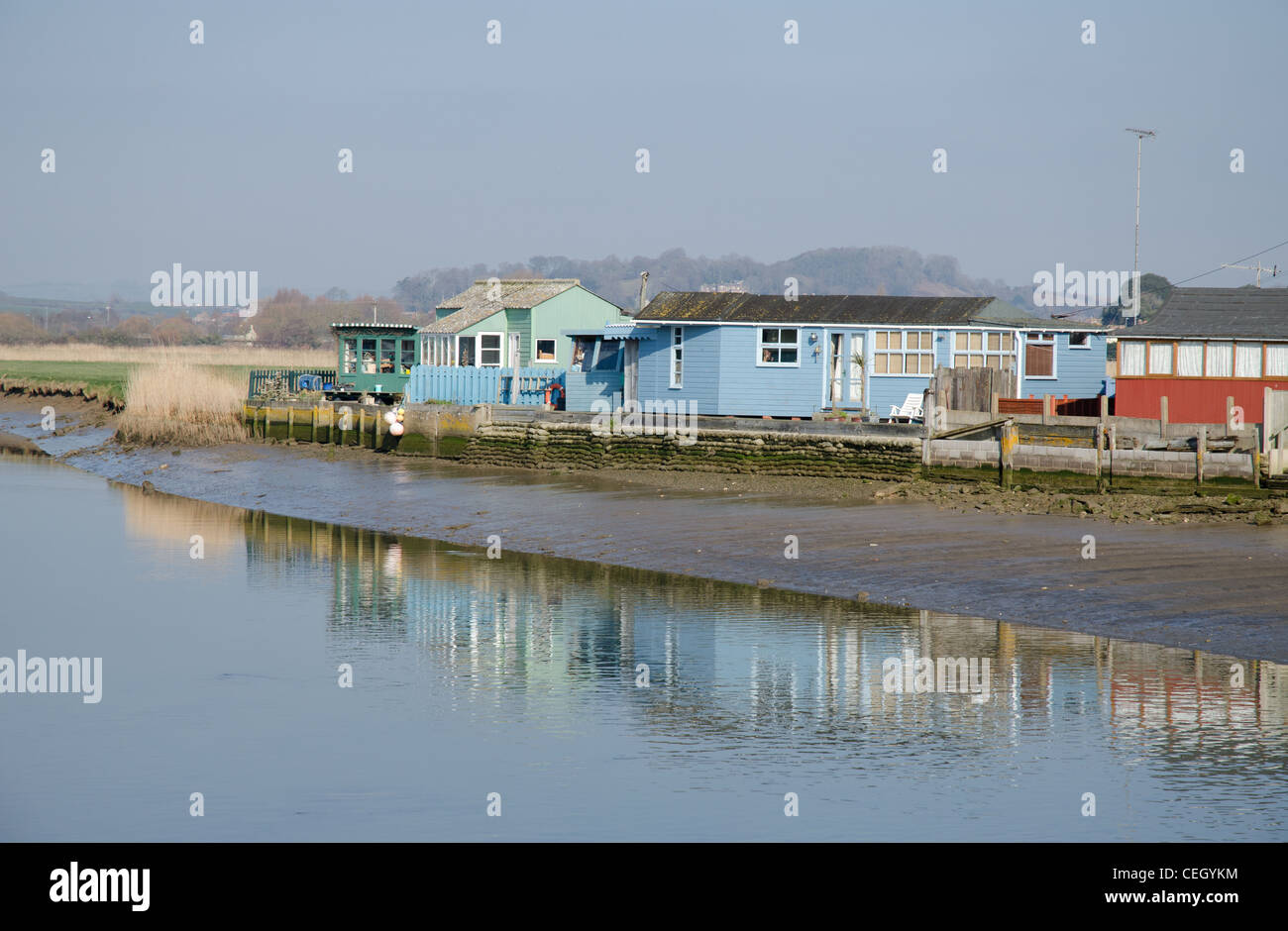 In legno pitturato capanne sulla spiaggia lungo il lato del fiume Brit a West Bay Dorset Regno Unito Foto Stock