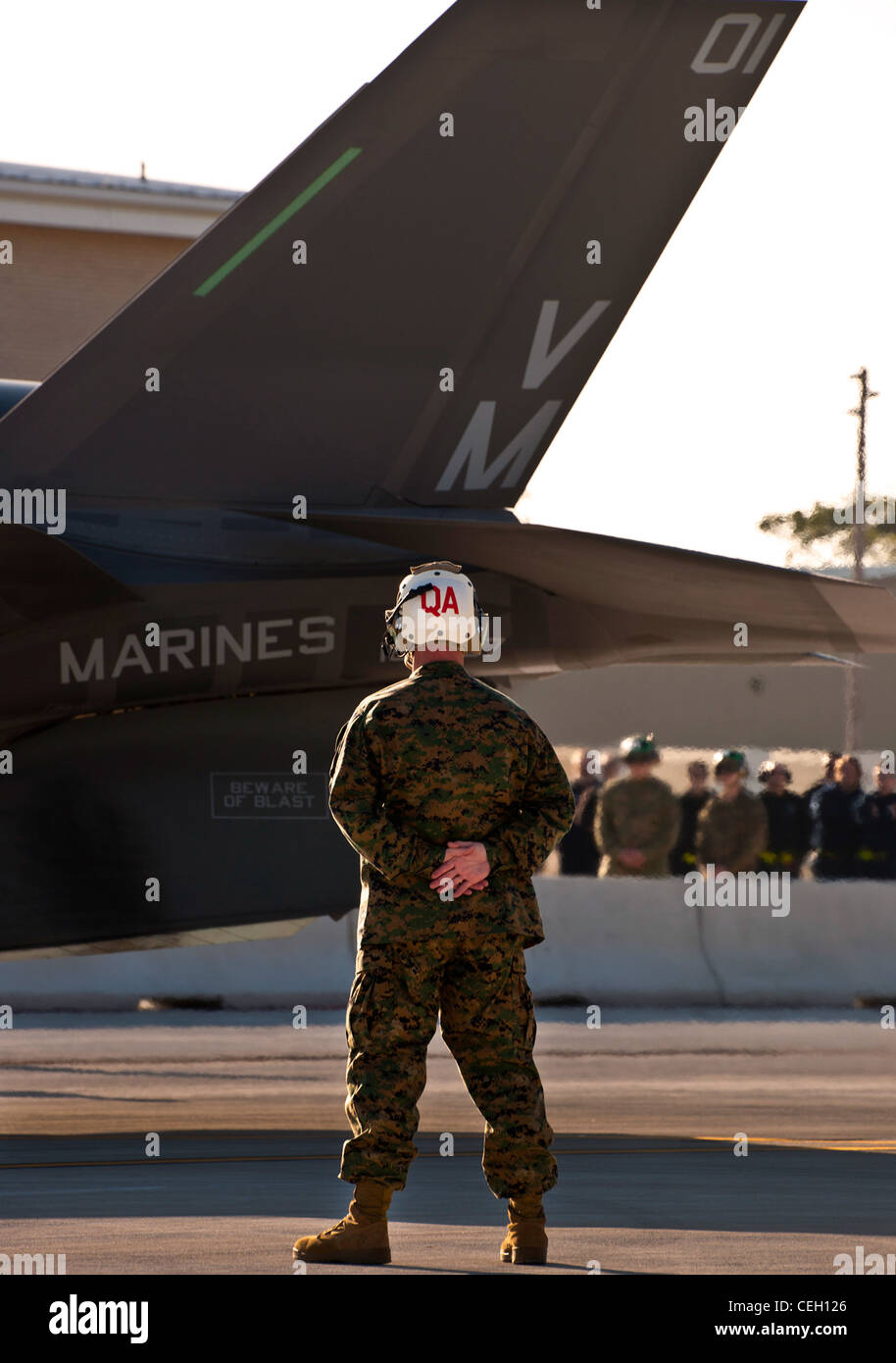 Un manutentore di Marine Fighter Attack Squadron 501 si erge come il primo combattente per sciopero congiunto Marine variante F-35B Lightning II è stato marshallato in posizione davanti allo squadrone della base dell'aeronautica di Eglin, la Fla. I Marines di VMFAT-501 hanno ricevuto due F-35Bs dal gennaio 11. Entrambi gli aeromobili sono stati scortati da Marine F-18 Hornets. Foto Stock