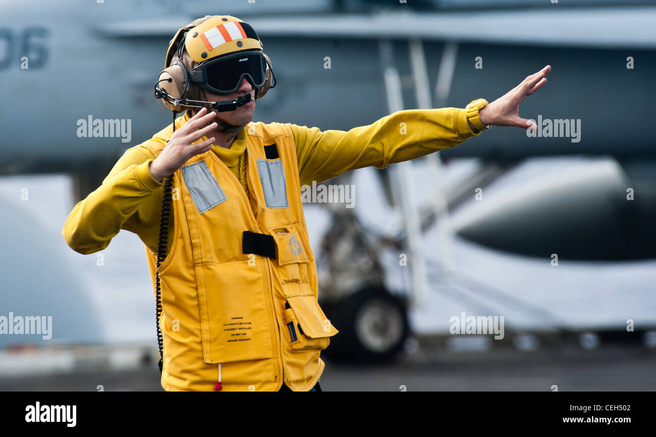 Aviation Boatswain's Mate (Handling) 3a Classe Michael Condlin, di Fayetteville, N.C., dirige un aereo ad ala fissa sul ponte di volo della portaerei di classe Nimitz USS John C. Stennis. John C. Stennis è in fase di distribuzione di sette mesi nella 7esima area di responsabilità della flotta statunitense. Foto Stock