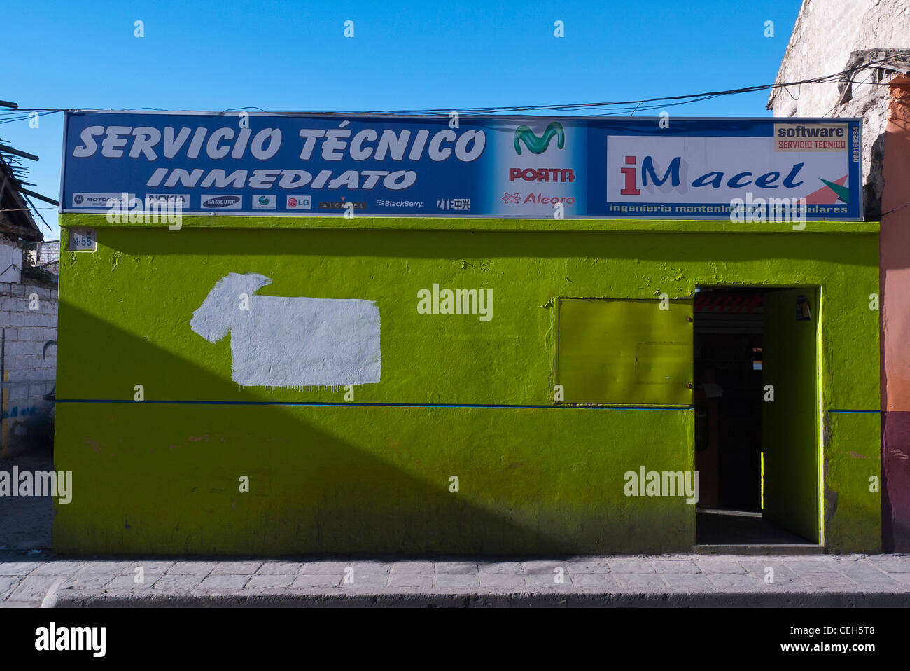Un brillante chartreuse edificio colorato che è un telefono cellulare officina di riparazione su una strada laterale a Latacunga, Ecuador. Foto Stock
