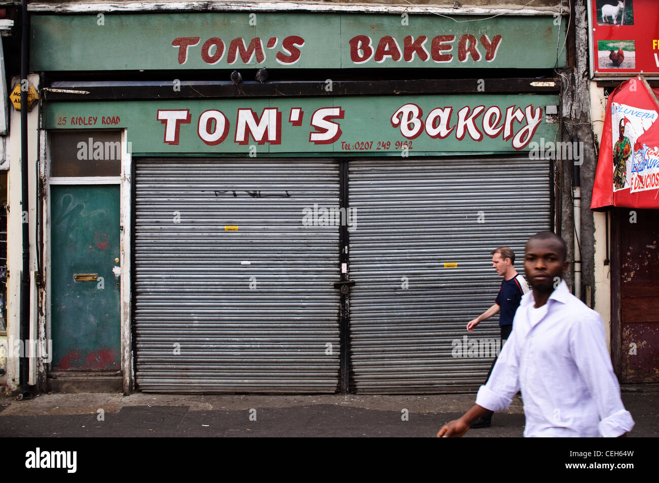 Due uomini a piedi passato Tom's panificio, un negozio di Ridley Road Market in Dalston, East London, England, Regno Unito. Foto Stock