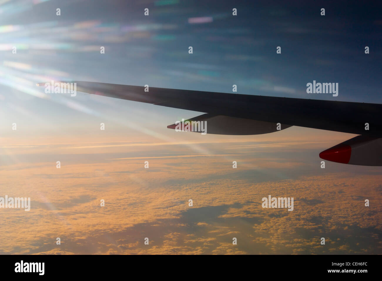 Vista da finestra sede dell'ala di aeroplano sopra lo strato di nuvola al tramonto Foto Stock