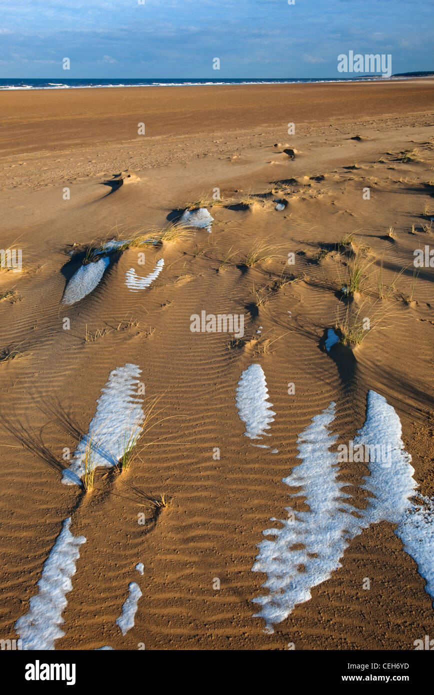 Neve che ricoprono le dune di sabbia e spiaggia a Holkham Bay sulla costa di Norfolk in inverno Foto Stock