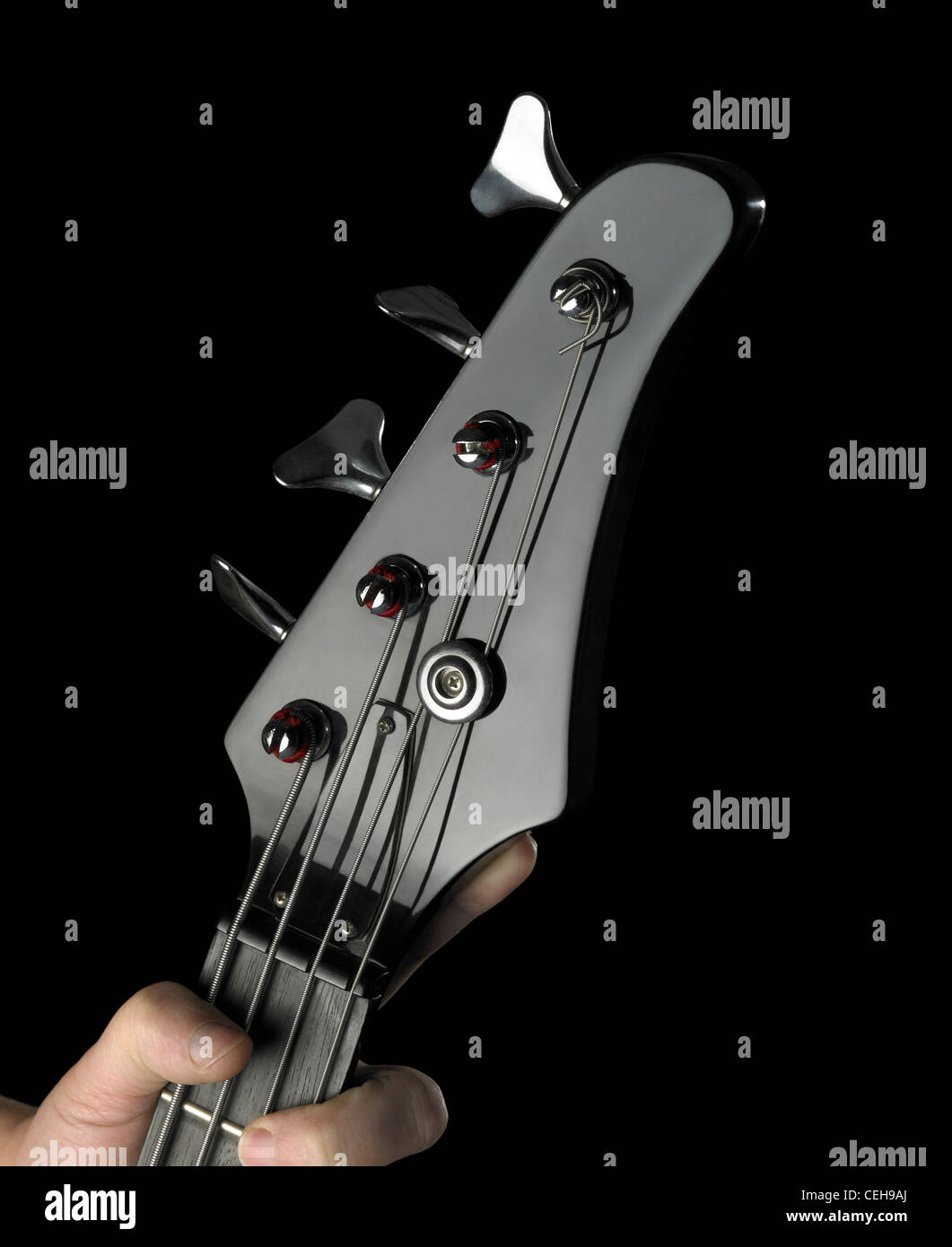 Dettaglio di un black bass chitarra e parte della mano tesa nel buio indietro Foto Stock