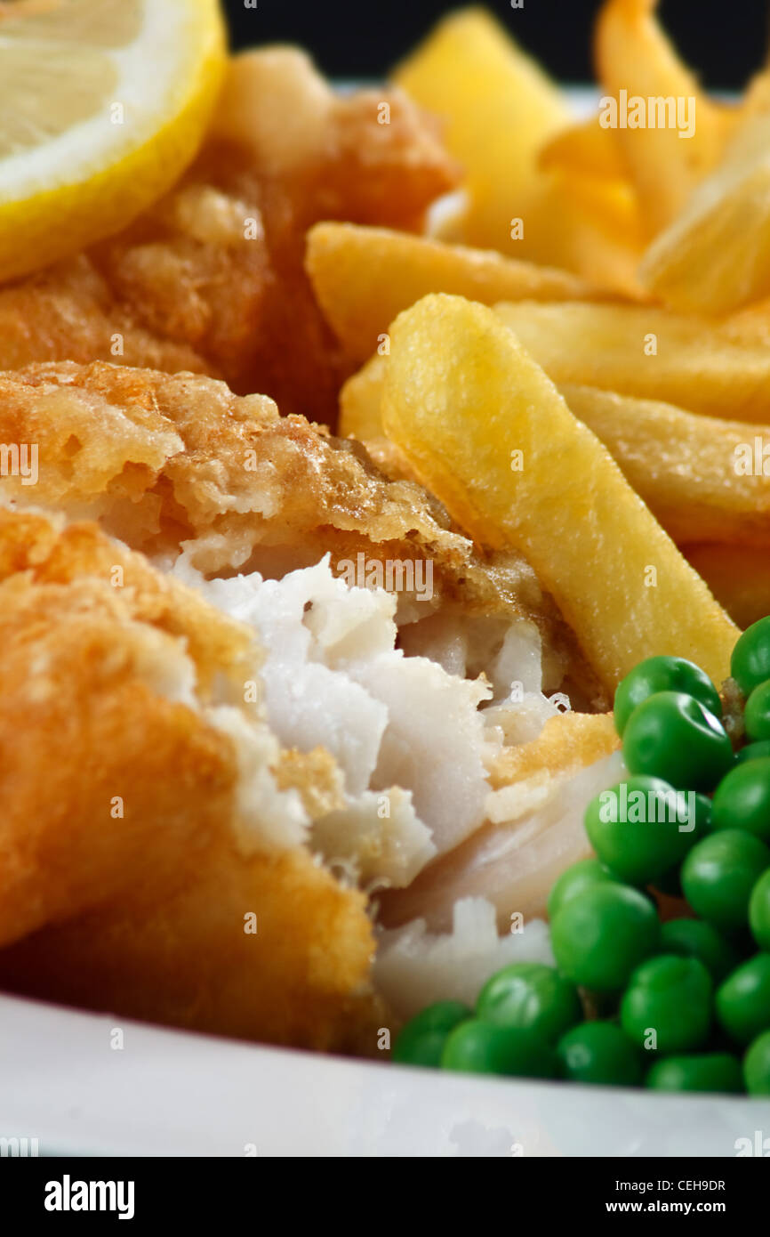 Close up di pesce e patatine con piselli e una fettina di limone. Un britannico tradizionale piatto di mare Foto Stock