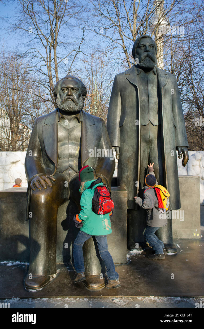 Bambini arrampicate sulle statue in bronzo di Marx e Engels in Alexanderplatz Mitte Berlino Germania Foto Stock