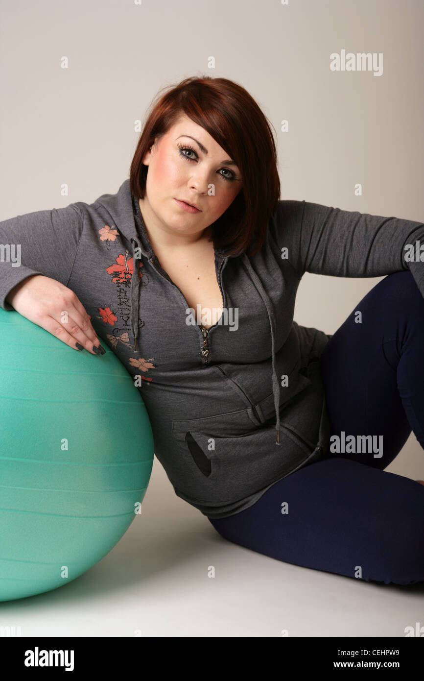 Donna seduta in appoggio contro una palla ginnica. Foto Stock
