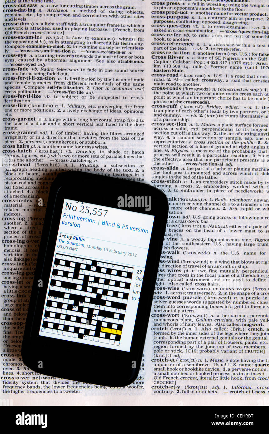 Un cruciverba online puzzle visualizzato su uno smartphone che posa in un dizionario che mostra la definizione del cruciverba. Foto Stock