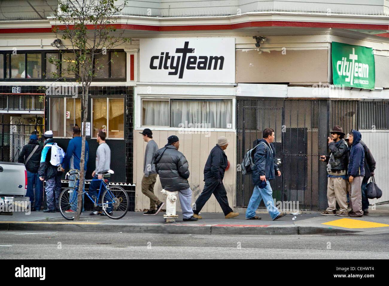 In serata, persone senza fissa dimora di entrambi i sessi immettere CityTeam Ministeri su 6th Street di San Francisco. Foto Stock