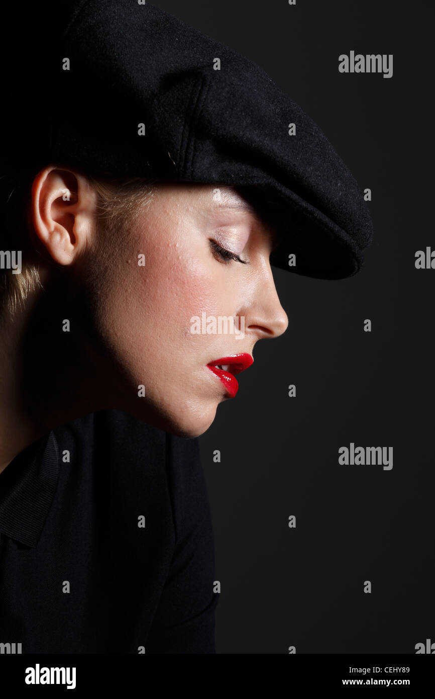 Una fotografia a colori di un bianco europeo il modello femminile che indossa un tappo piatto con forte rossetto rosso Foto Stock