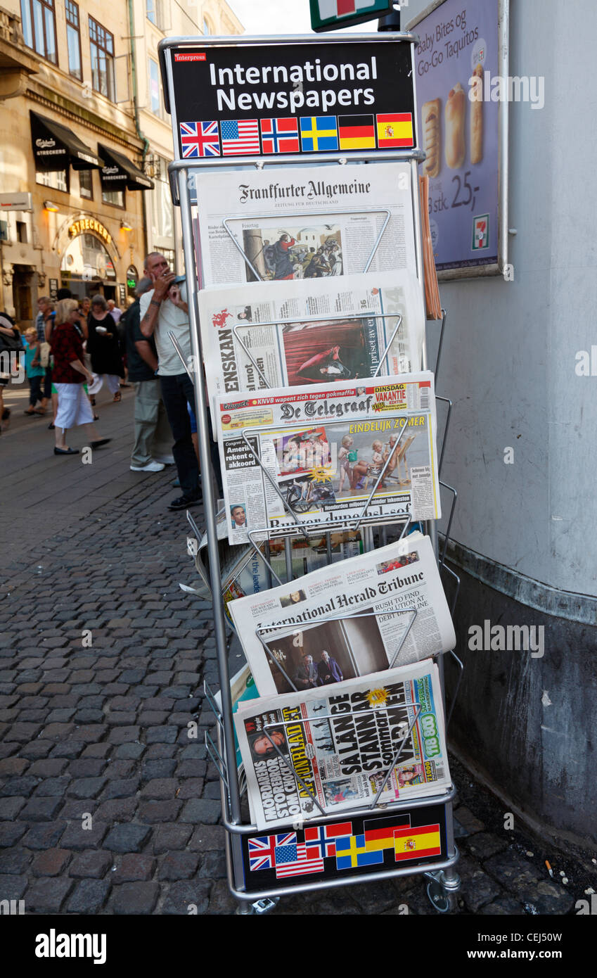 Rastrelliera di giornali con giornali quotidiani internazionali al di fuori di un edicola a Strøget, la principale strada pedonale e la strada dello shopping di Copenaghen Foto Stock