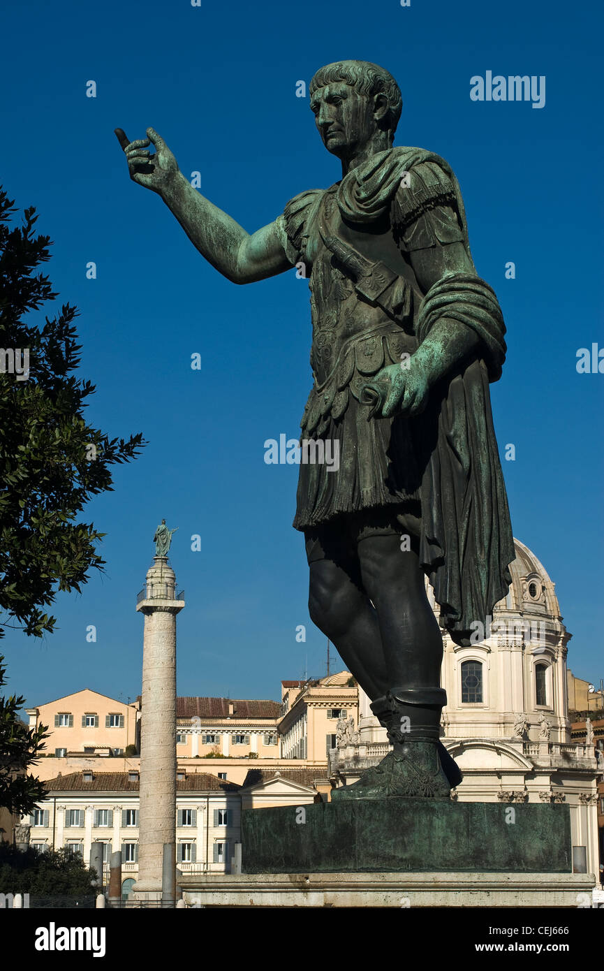 Statua dell'imperatore Traiano, Colonna di Traiano in background, Roma, Lazio, Italia Foto Stock