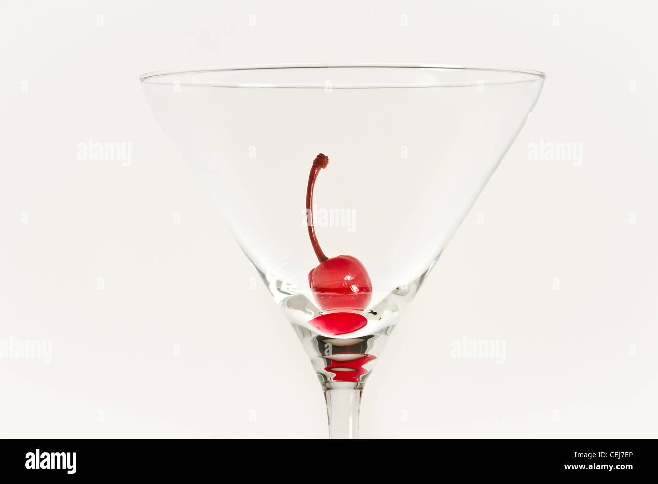 Una ciliegia nel bicchiere vuoto isolato su sfondo bianco Foto Stock