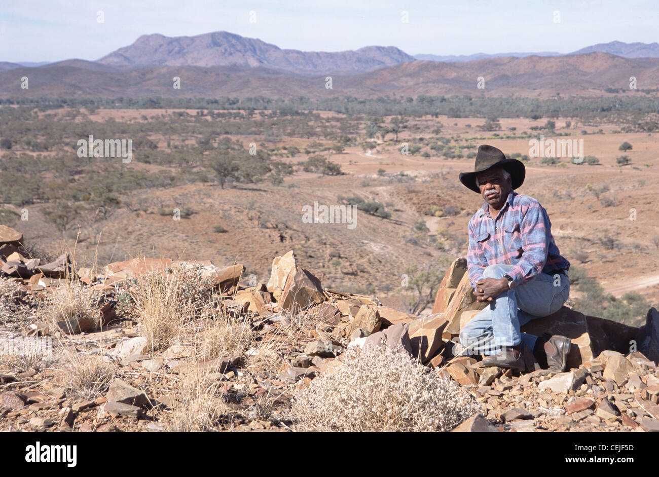 Aboriginal uomo seduto su una roccia nel Flinders Ranges, Sud Australia Foto Stock