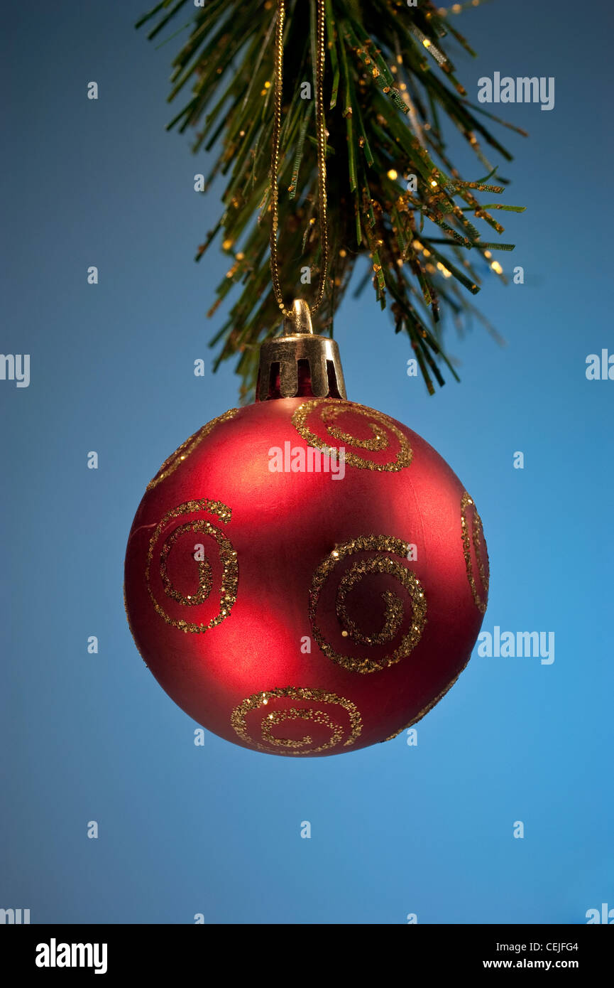 Un rosso palla di Natale decorazione contro uno sfondo blu Foto Stock