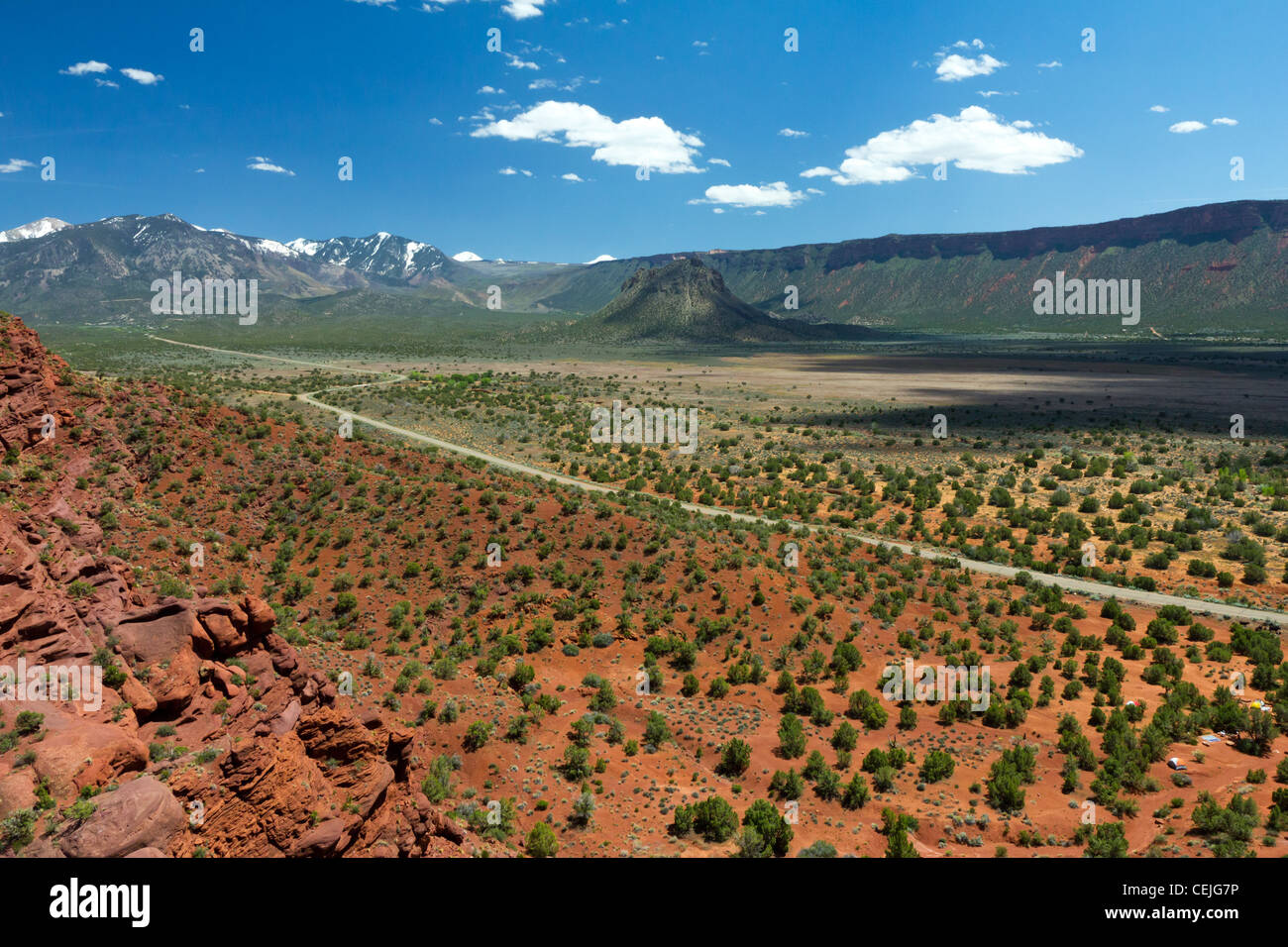 Lunga strada vuota viaggia attraverso il canyon del deserto del sud-ovest americano vicino al Parco Nazionale di Arches al di fuori di Moab Utah. Foto Stock
