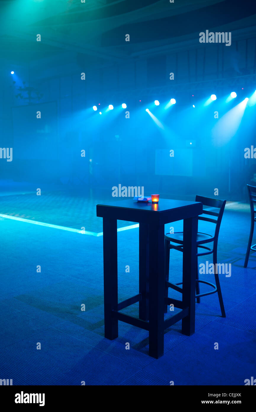Discoteca club bar dance music hall di bere alcol divertente vita notturna di inibizioni da sola sedia tavolo uno blu Foto Stock
