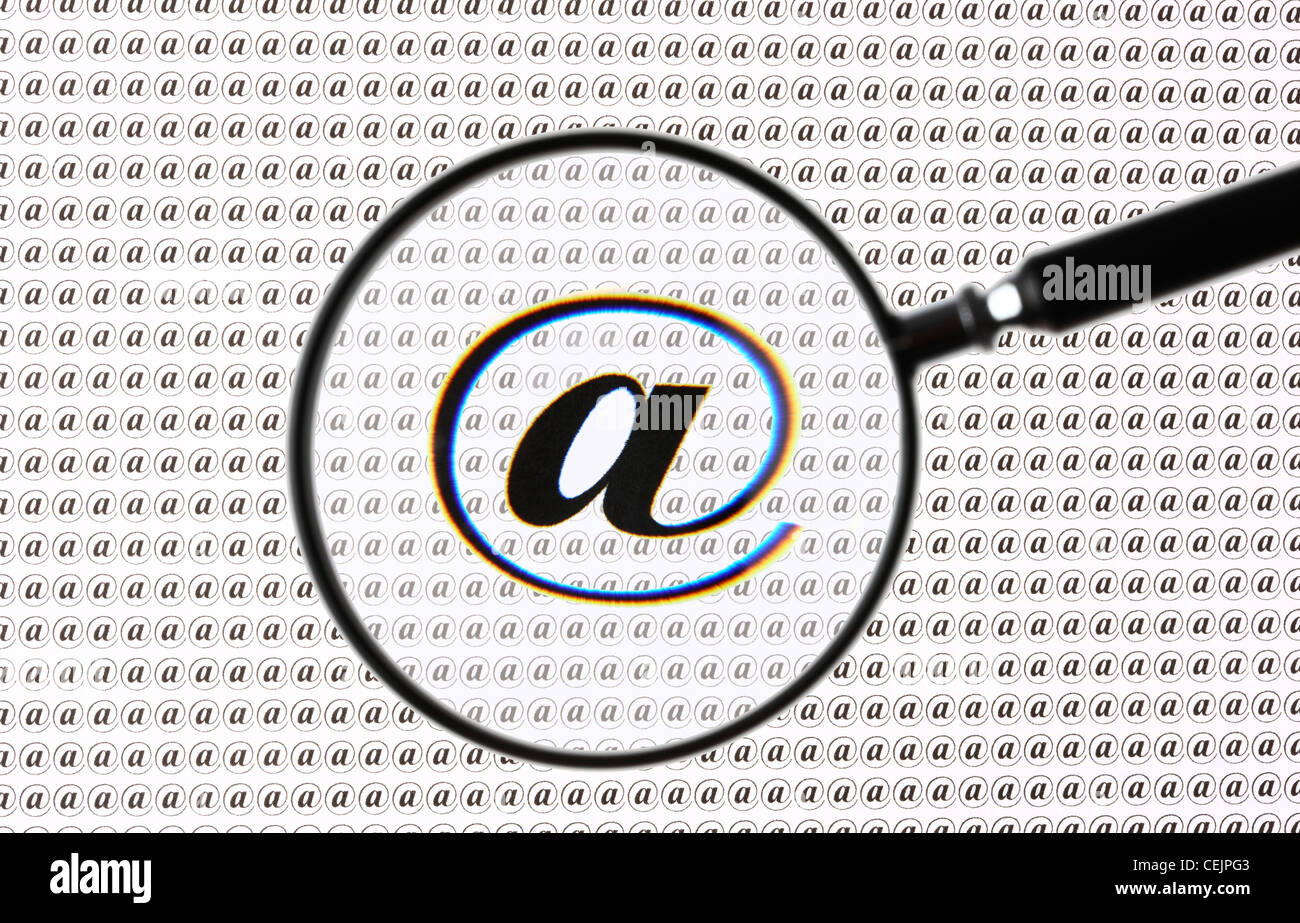 Lente di ingrandimento evidenziando un segno @, Internet, E-mail simbolo. Immagine simbolica. Foto Stock