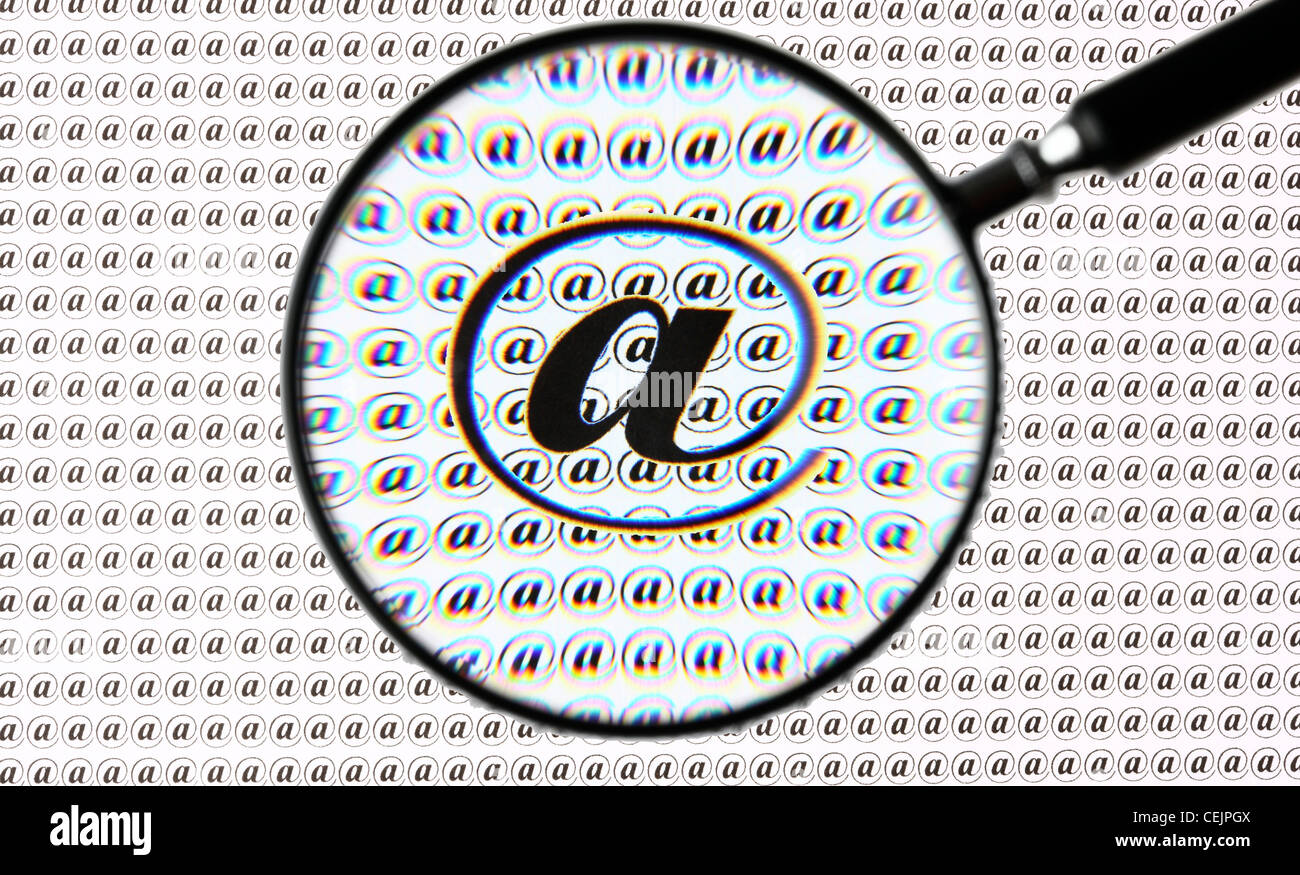 Lente di ingrandimento evidenziando un segno @, Internet, E-mail simbolo. Immagine simbolica. Foto Stock