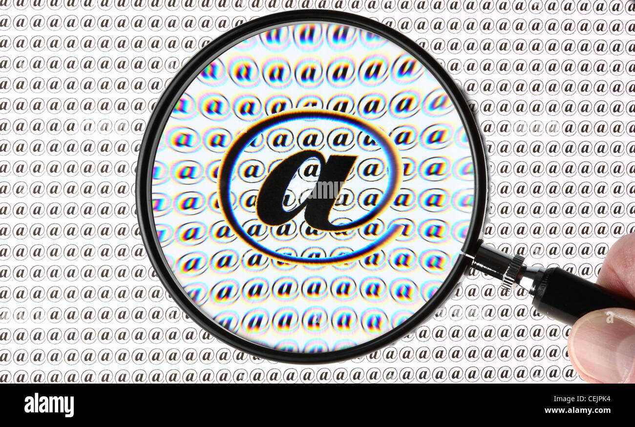 Lente di ingrandimento evidenziando un segno @, Internet, E-mail simbolo. Immagine simbolica. Foto Stock