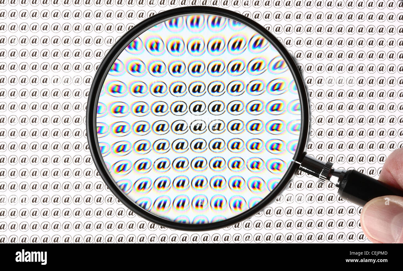Lente di ingrandimento evidenziando un segno @, Internet, E-mail simbolo. Immagine simbolica. Foto Stock